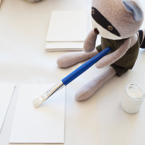 Max Racoon paints a canvas with gesso
