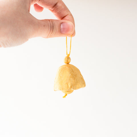a hand holding a bell with the clapper ball visible 